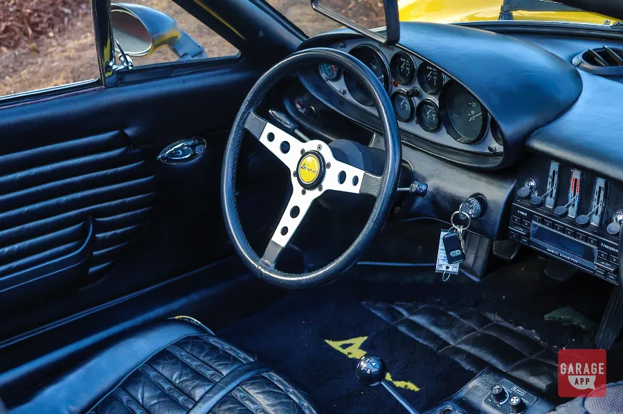Interior of a Giallo Fly yellow Ferrari Dino 246 GT featuring a gated manual shifter, classic analog gauges, and a driver-focused cockpit that embodies the analog Ferrari driving experience.