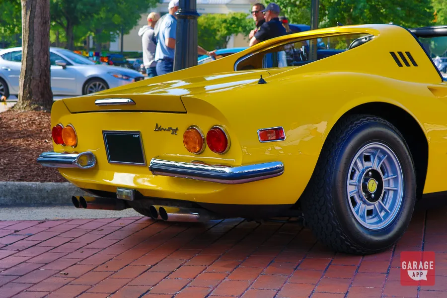 Rear view of a Ferrari Dino 246 GT finished in Giallo Fly yellow, showcasing chrome accents and classic Ferrari rear styling.