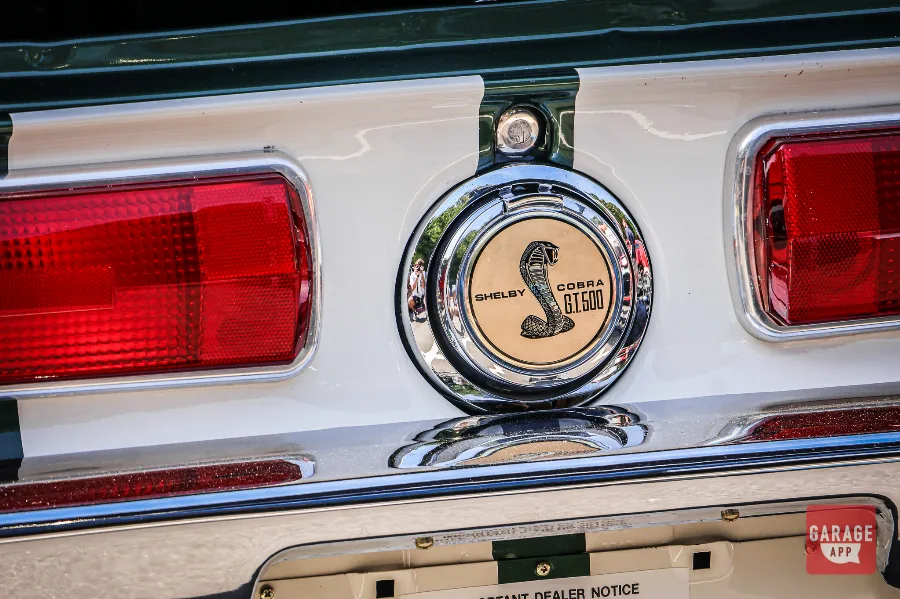 Close-up of the Shelby Cobra GT500 fuel cap emblem on a dark green 1968 Shelby GT500 fastback at Fuquay-Varina Cars and Coffee.