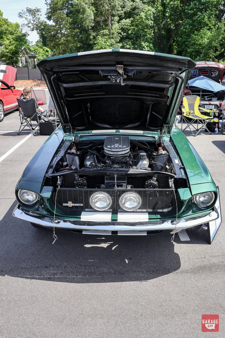 Front view of a dark green 1968 Shelby GT500 with the hood open, revealing the detailed engine bay.