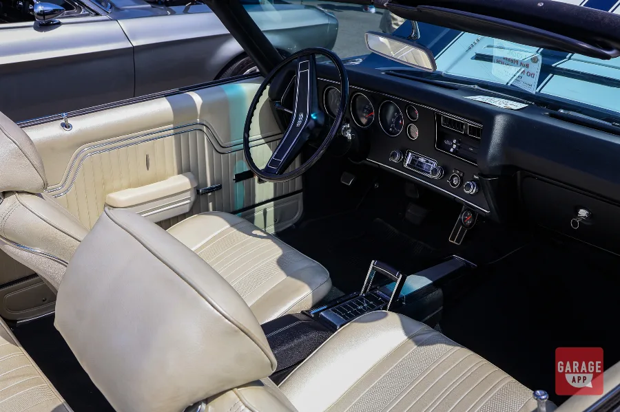 Interior of a 1970 Chevrolet Chevelle SS 454 Convertible featuring cream bucket seats, factory dashboard, and center console at a classic car show.