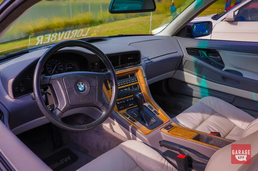 Gray leather interior and dashboard of a 1995 BMW 840Ci E31 featuring wood trim, analog gauges, and luxury grand touring amenities.