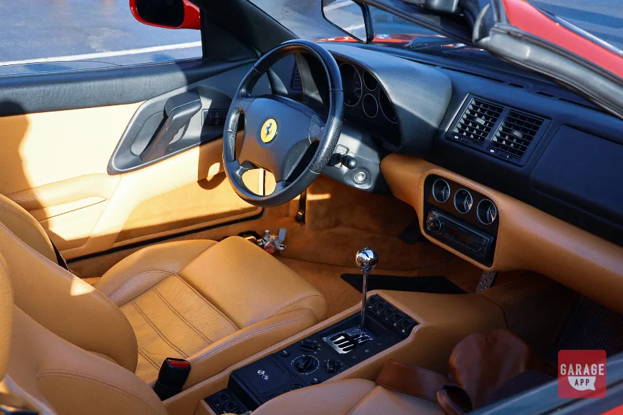 Tan leather interior of a Ferrari F355 Spider featuring the driver's cockpit and center console.