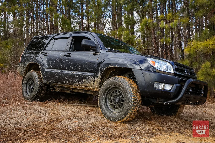 2005 Toyota 4Runner V8 lifted SUV covered in mud during an off-road trail ride in the woods.