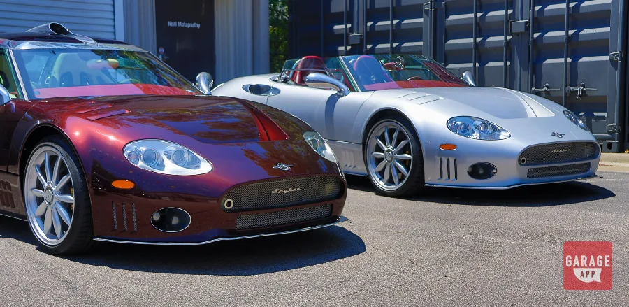 A 2009 Spyker C8 Laviolette in Madeira Red sits beside a 2006 Spyker C8 Spyder in Champion Silver, showcasing two rare handcrafted Dutch supercars.