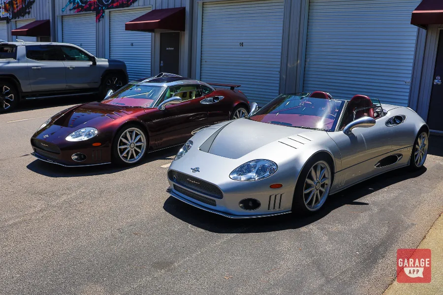 A Champion Silver Spyker C8 Spyder and Madeira Red C8 Laviolette photographed from a three-quarter angle outside Carolina Exotic Car Club.