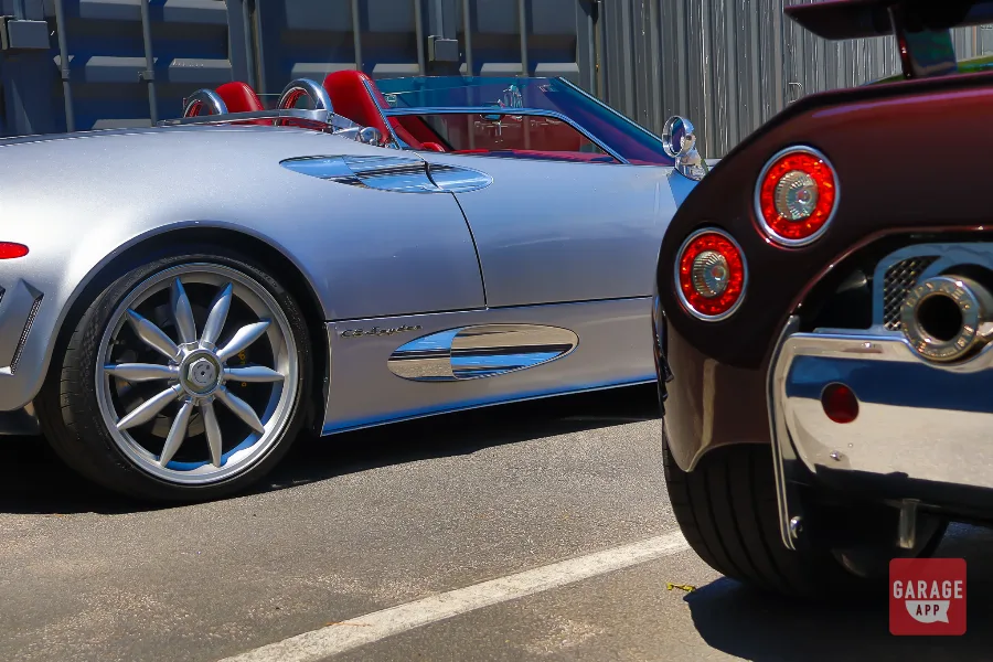 Side profile of the Spyker C8 Spyder with the C8 Laviolette in the background, highlighting the signature polished side intakes and distinctive body lines.