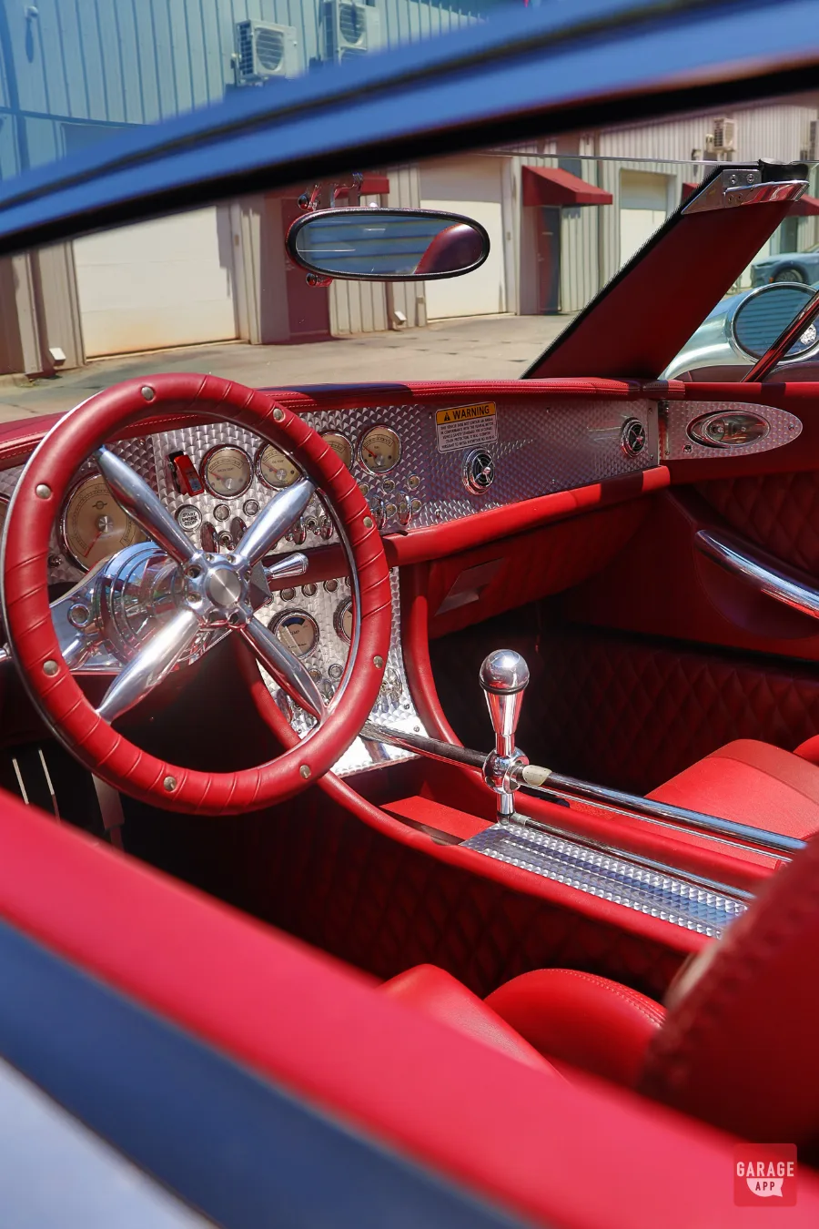 Red leather interior of a 2006 Spyker C8 Spyder featuring a polished aluminum dashboard, exposed shifter, and aircraft-inspired steering wheel.