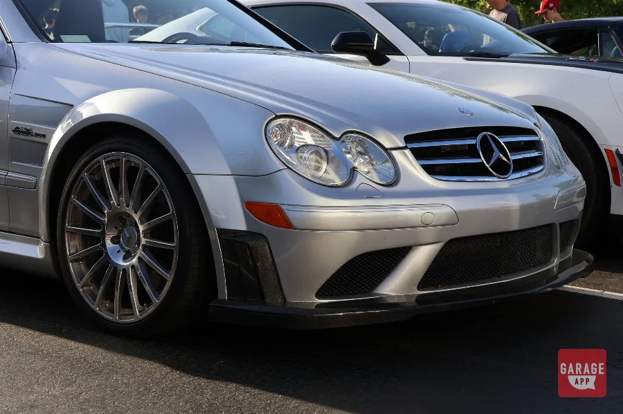 Low front angle of a 2009 Mercedes-Benz CLK 63 AMG Black Series in Iridium Silver Metallic, highlighting the aggressive front bumper, carbon fiber splitter, and AMG styling.