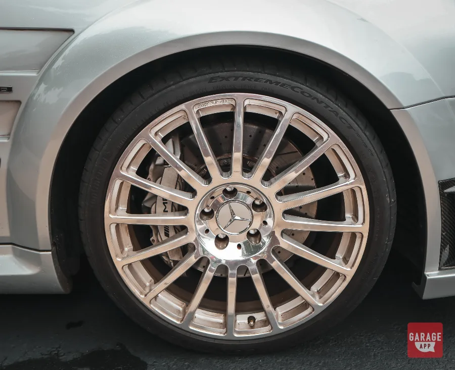 Close-up of the factory AMG forged wheel on a 2009 Mercedes-Benz CLK 63 AMG Black Series in Iridium Silver Metallic, showcasing the performance brake system and widebody stance.