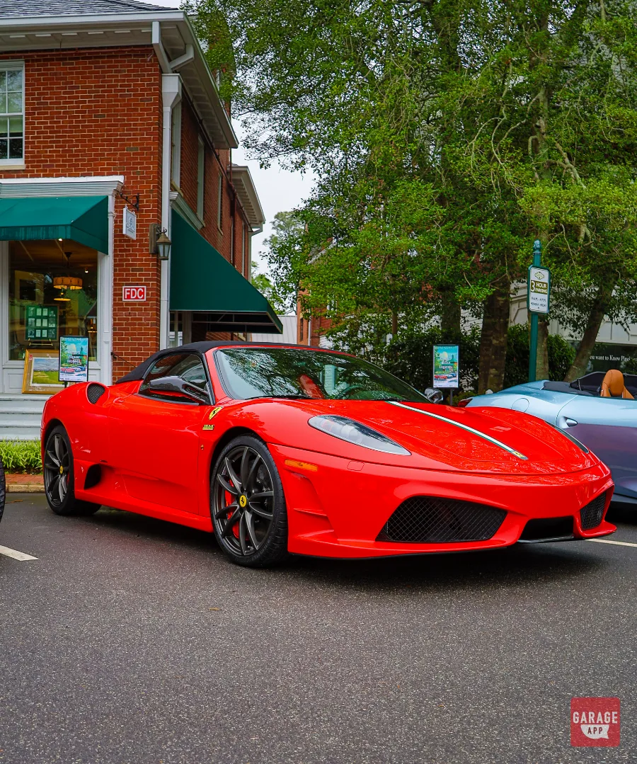 2009 Ferrari F430 Scuderia Spider 16M in Rosso Corsa displayed at a luxury car event from the front driver-side three-quarter angle.