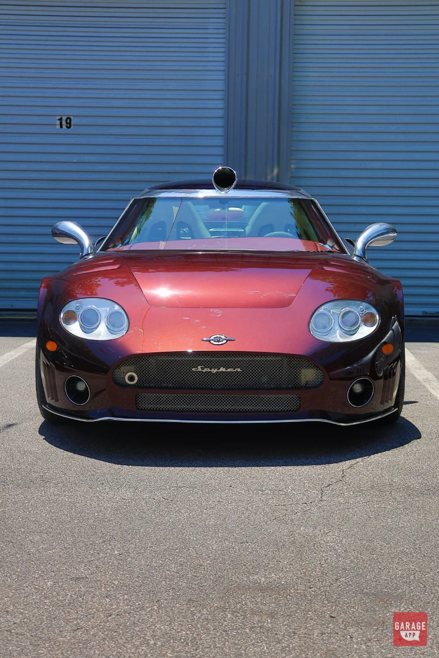 Head-on view of a 2009 Spyker C8 Laviolette in Madeira Red parked outside Carolina Exotic Car Club.