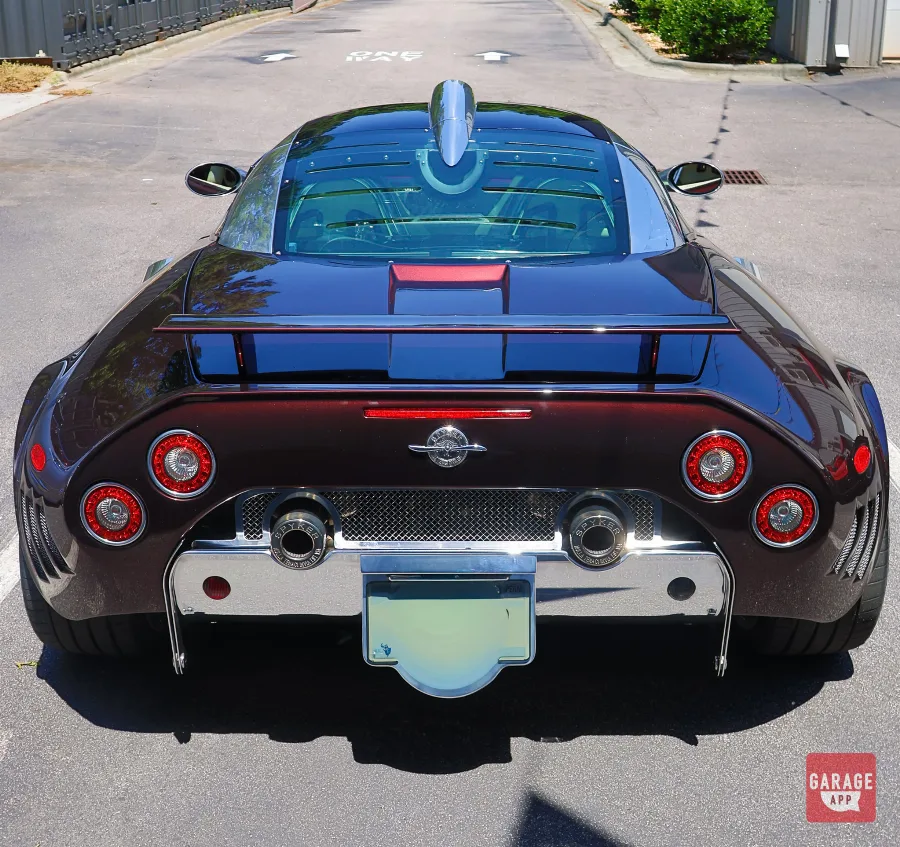 Rear view of a 2009 Spyker C8 Laviolette in Madeira Red, highlighting its dual exhaust system, rear wing, and signature circular taillights.