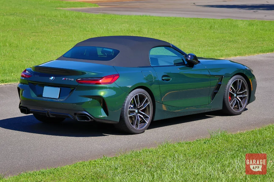 Side-rear perspective of a BMW Z4 M40i manual in San Remo Green, showcasing the muscular rear haunches and soft-top roadster design.