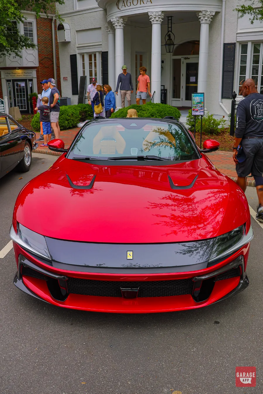 Front elevation view of a 2025 Ferrari 12Cilindri Spider in Rosso Corsa at the Pinehurst Concours showing Daytona-inspired styling and carbon fiber details.