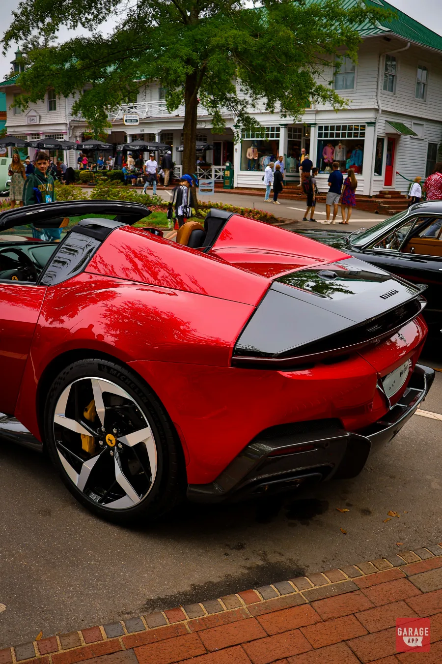 Rear three-quarter view of a 2025 Ferrari 12Cilindri Spider in Rosso Corsa highlighting the Daytona-inspired rear design and open-top configuration.