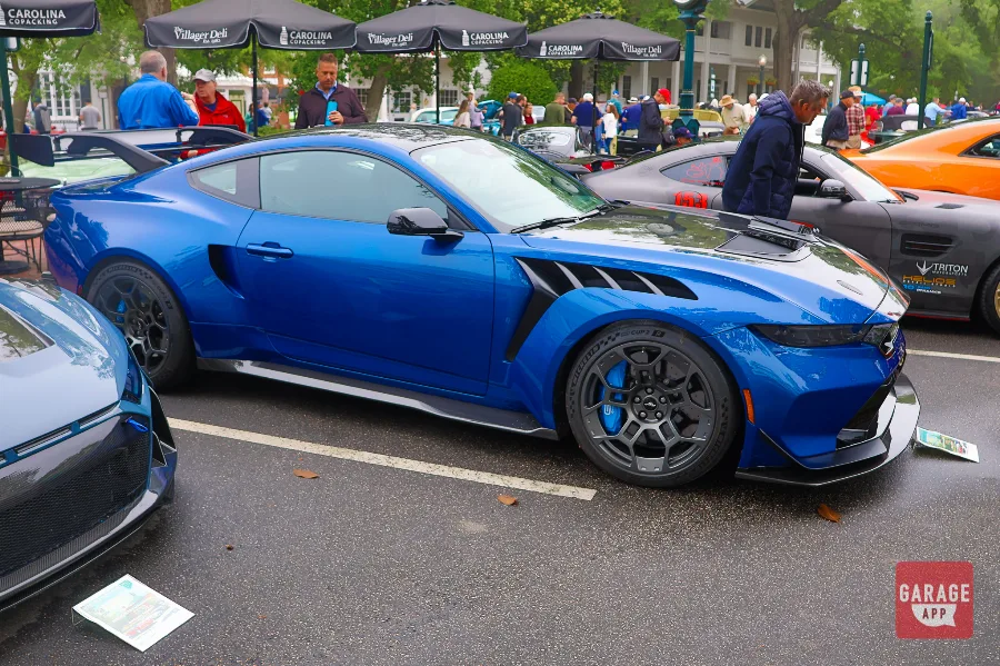 Three-quarter driver side view of a blue 2025 Ford Mustang GTD at a car show, highlighting the aggressive front fascia, performance wheels, and race-inspired body design.