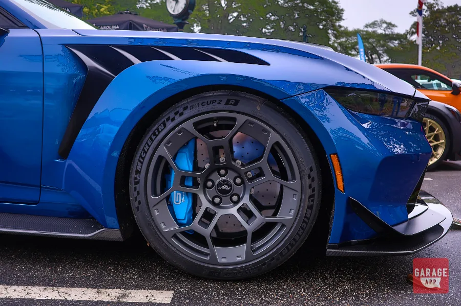 Front wheel, carbon fiber fender, and aerodynamic vent detail on a blue 2025 Ford Mustang GTD equipped with Michelin Pilot Sport Cup 2 R tires and high-performance Brembo brakes.