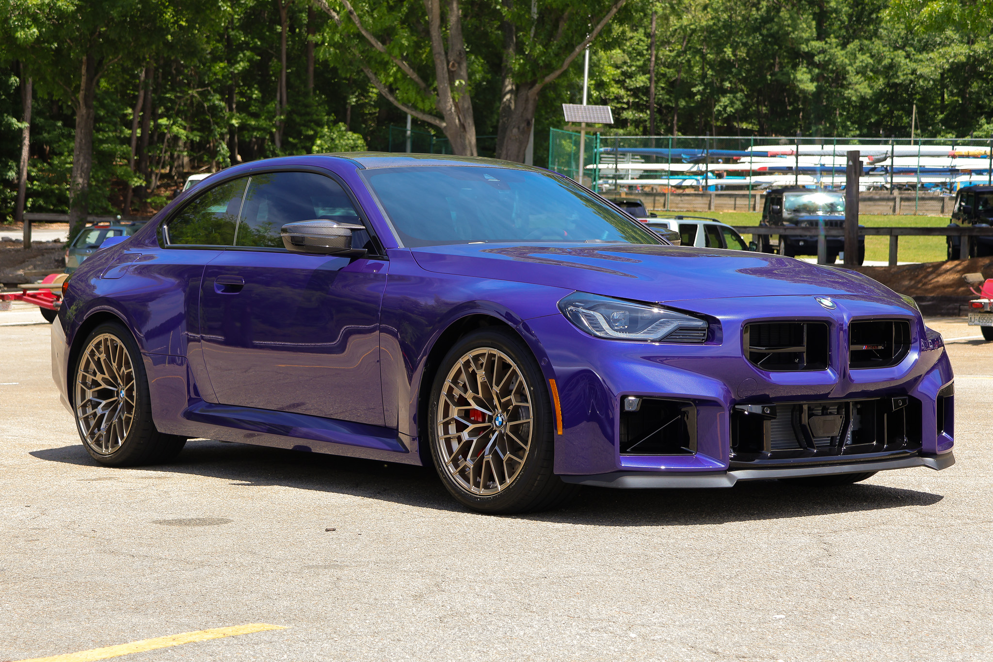 Front three-quarter view of a 2026 BMW M2 CS in Velvet Blue with carbon fiber accents and bronze wheels.