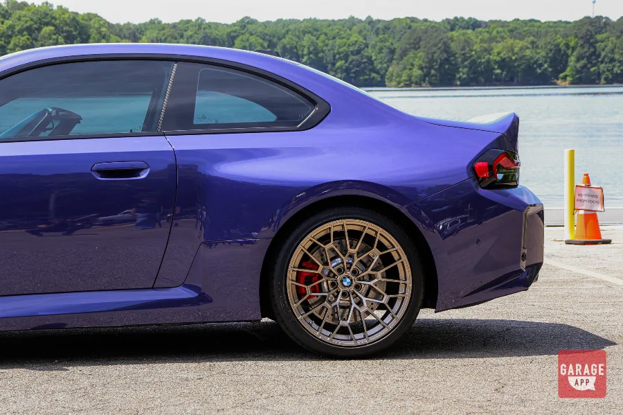 Rear quarter detail of a 2026 BMW M2 CS in Velvet Blue featuring bronze wheels, red brake calipers, and wide rear fenders.