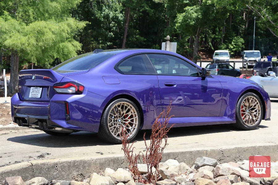 Rear three-quarter view of a 2026 BMW M2 CS in Velvet Blue showcasing the sculpted rear design and performance exhaust system.