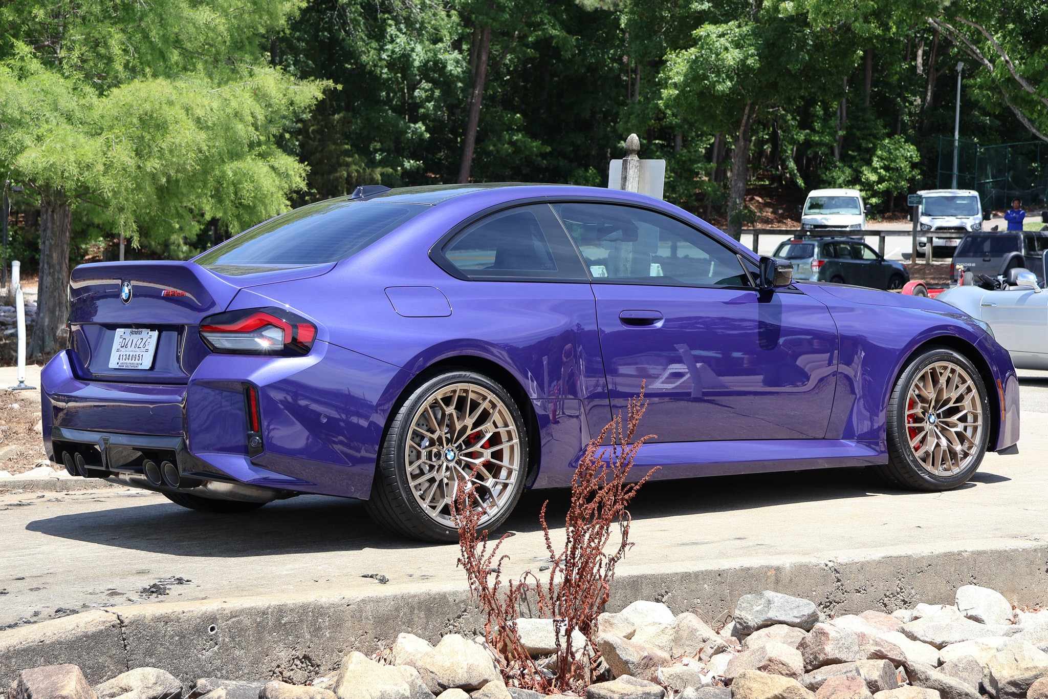 Rear three-quarter view of a 2026 BMW M2 CS in Velvet Blue showcasing the sculpted rear design and performance exhaust system.
