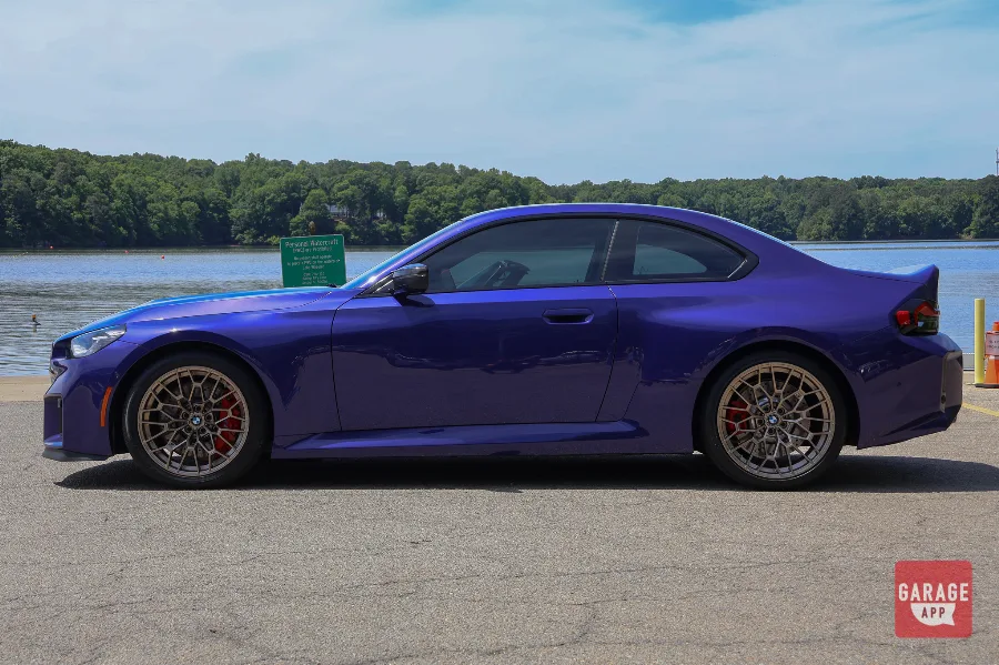 Side profile of a 2026 BMW M2 CS in Velvet Blue featuring bronze forged wheels and the signature G87 coupe silhouette.