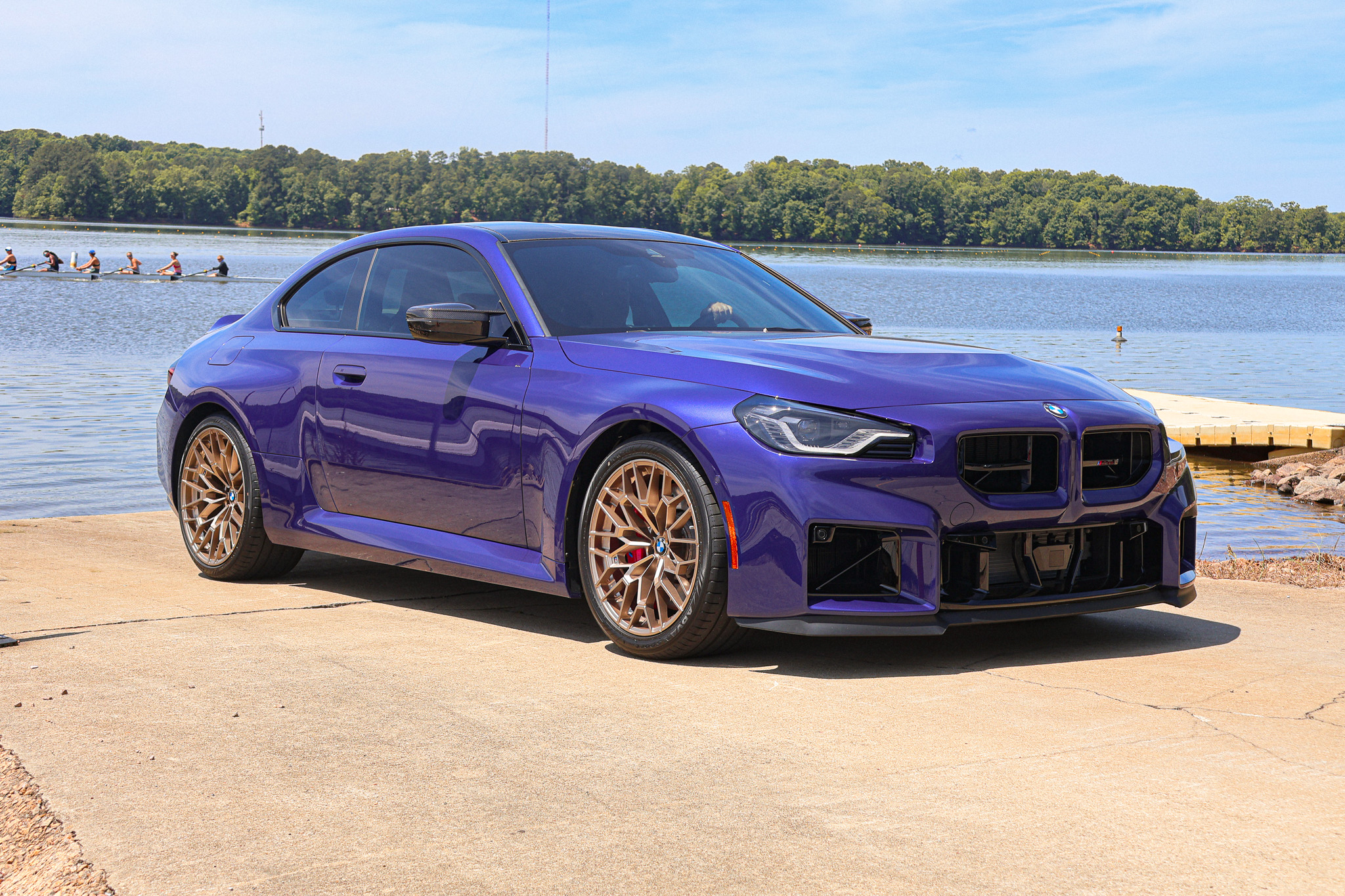 2026 BMW M2 CS in Velvet Blue parked near the waterfront, photographed from a front three-quarter perspective.