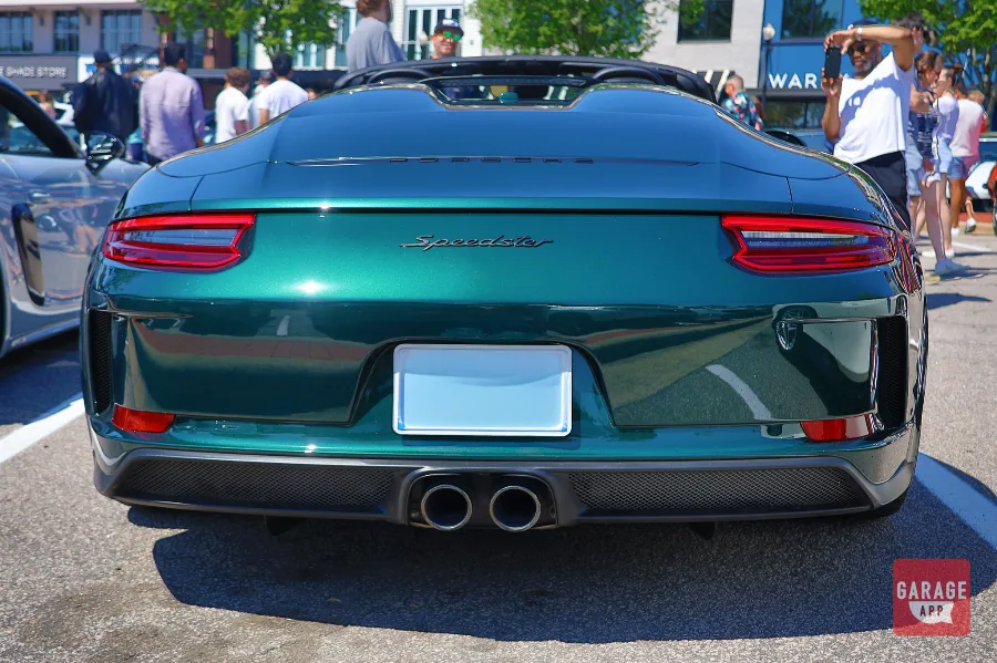 Rear three-quarter angle of a green 911 Speedster displaying the wide rear haunches, taillights, and dual exhaust system.