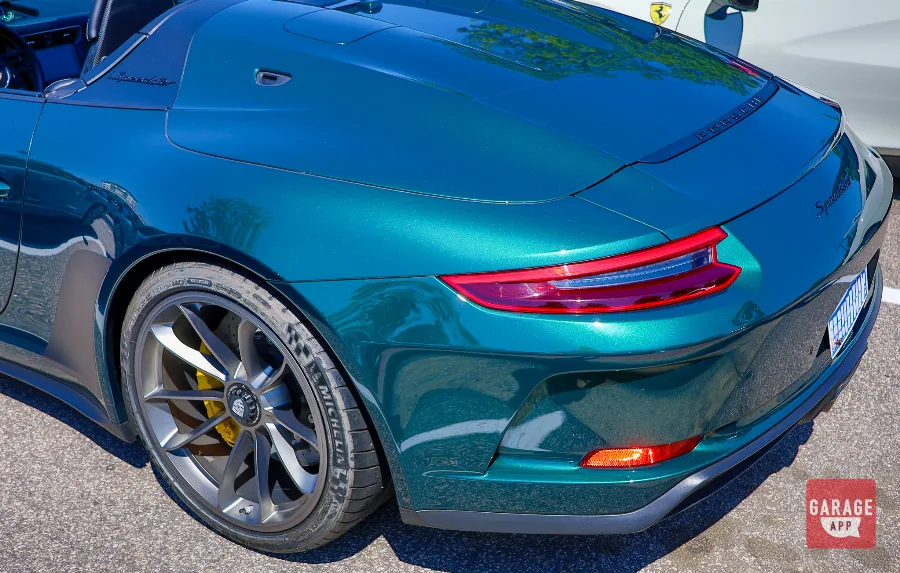 Side profile of a green Porsche 911 Speedster highlighting its classic silhouette, low windshield, and double-bubble rear deck.