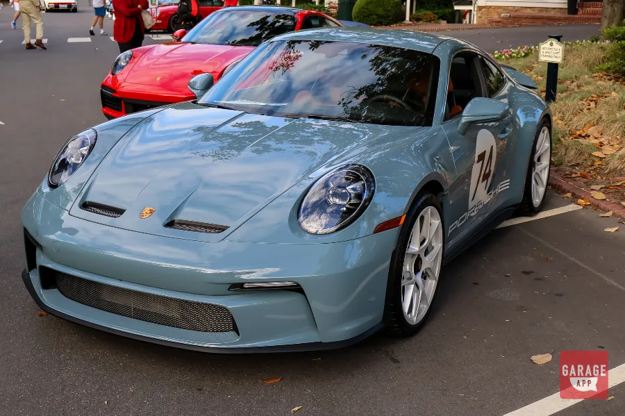 Front three-quarter view of a 2024 Porsche 911 S/T finished in Shore Blue Metallic, showcasing the lightweight design and timeless Porsche styling.