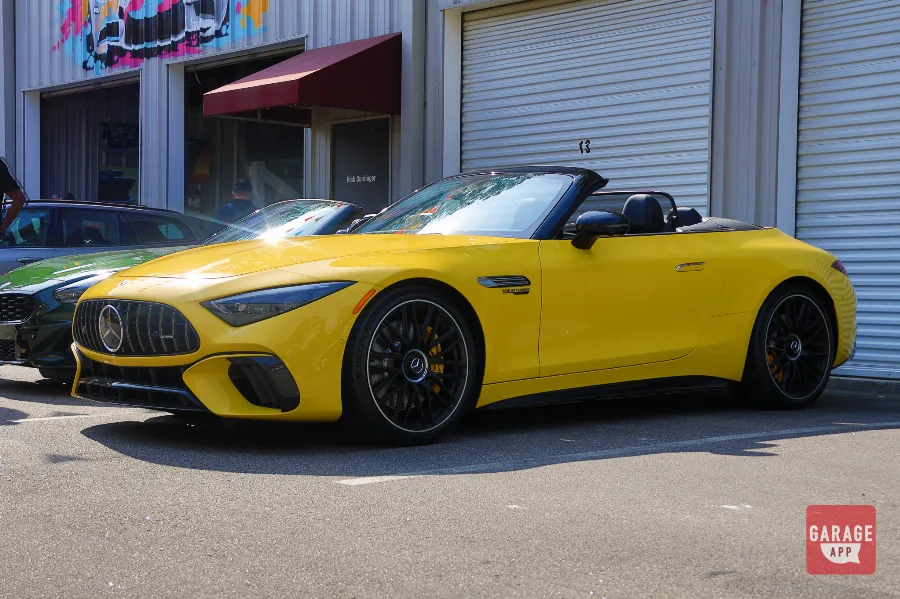 Front three-quarter view of a 2025 Mercedes-AMG SL 63 in MANUFAKTUR Sun Yellow, showcasing the Panamericana grille, aggressive styling, and luxury performance design.