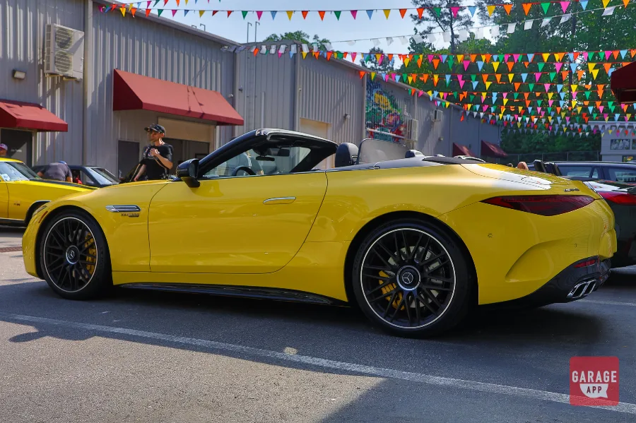 Rear three-quarter view of a 2025 Mercedes-AMG SL 63 in MANUFAKTUR Sun Yellow, showcasing the sculpted rear bodywork and elegant roadster proportions.
