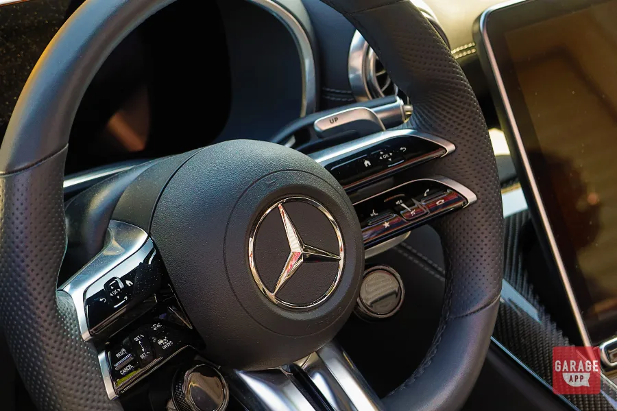 Close-up of the AMG Performance steering wheel inside a 2025 Mercedes-AMG SL 63, featuring premium materials, aluminum paddle shifters, and integrated drive controls.