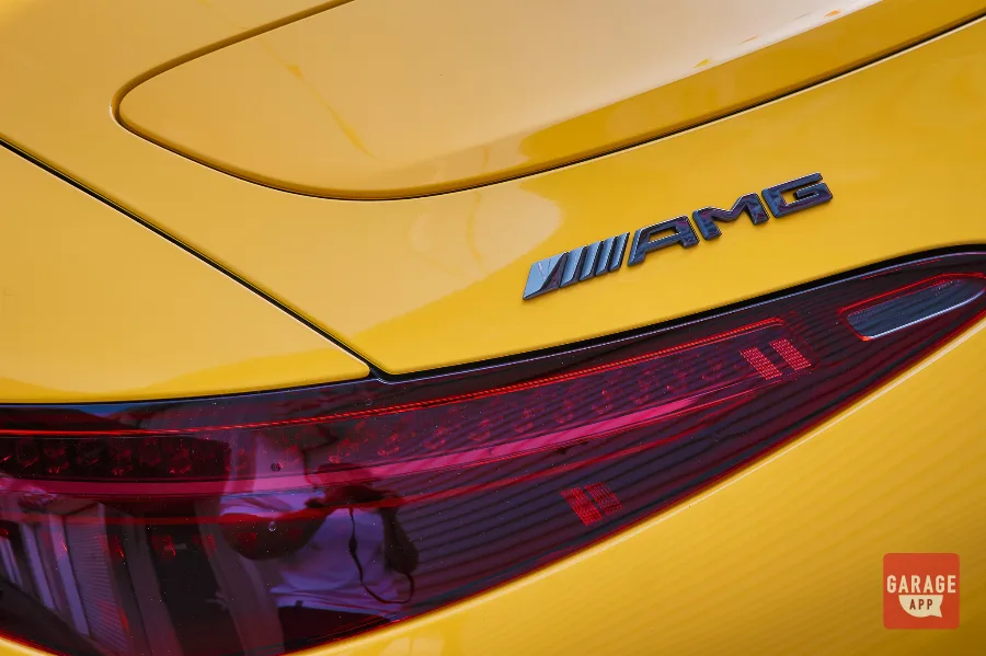 Close-up of the AMG badge and LED taillight on a 2025 Mercedes-AMG SL 63 in MANUFAKTUR Sun Yellow, highlighting the luxury roadster's signature rear styling.