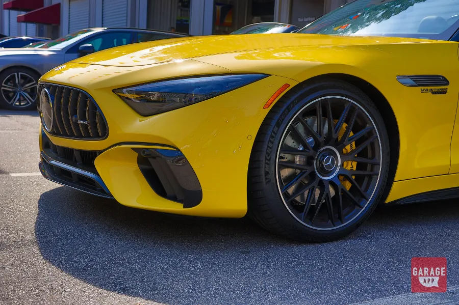 Close-up of the AMG forged wheel on a 2025 Mercedes-AMG SL 63 in MANUFAKTUR Sun Yellow, featuring Michelin performance tires and a high-performance braking system.