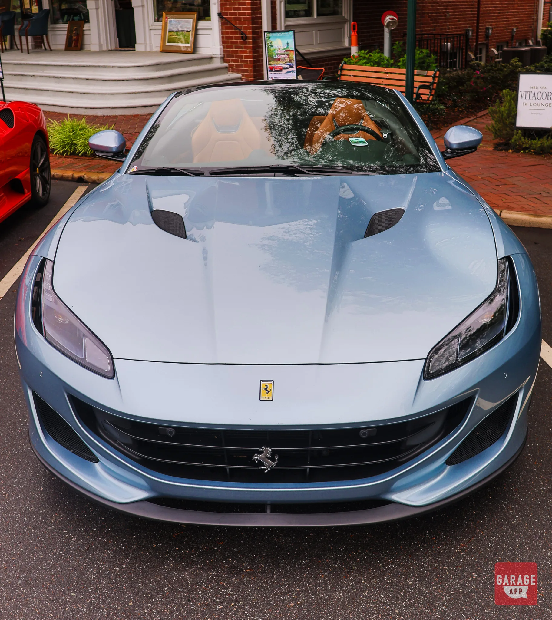 Side profile of a red 2019 Ferrari Portofino convertible with retractable hardtop fully retracted on a coastal road