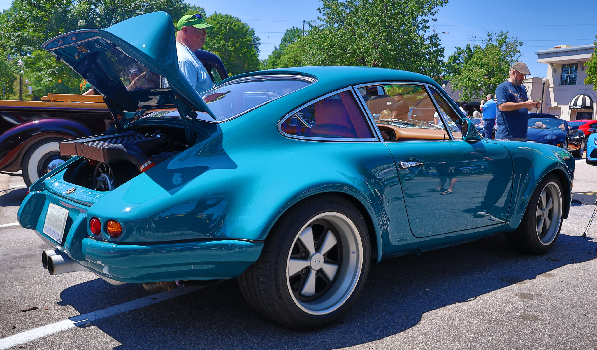 Wide-bodied air-cooled Singer Porsche 911 with deep-dish Fuchs-style wheels parked at a coastal road