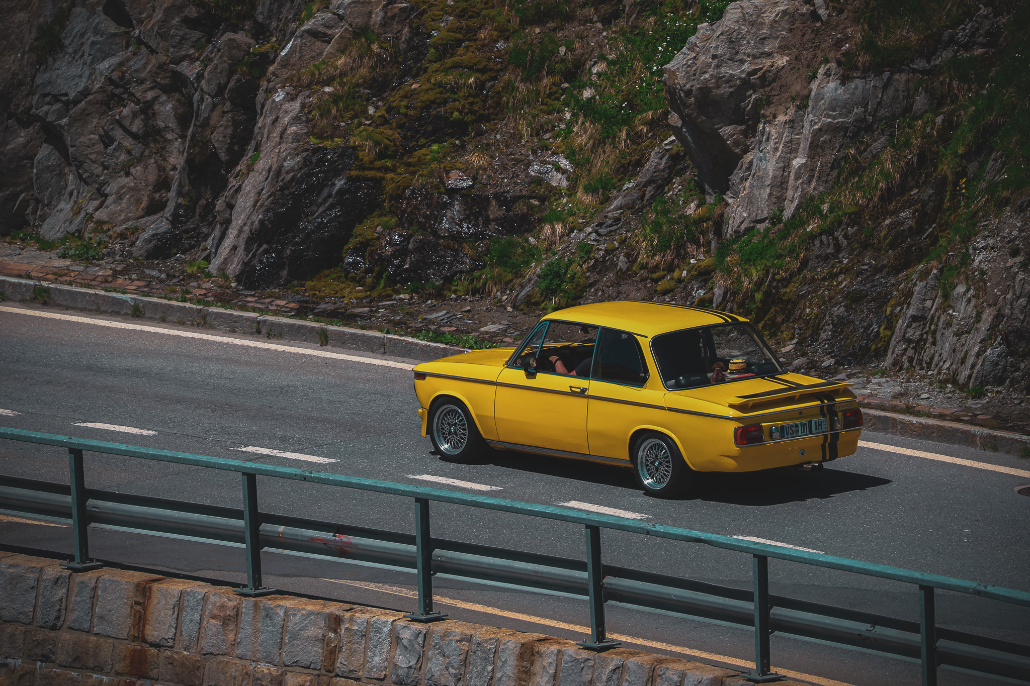 Yellow BMW 2002 rear three-quarter view Furka Pass road