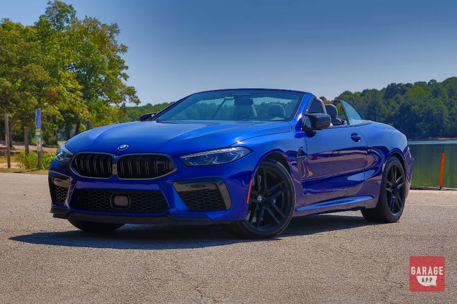 Low-angle front view of blue BMW M8 Competition Convertible at a lakeside lot