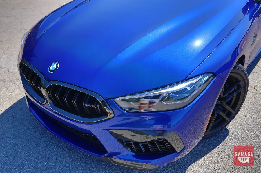 Top-down view of blue BMW M8 Competition hood, kidney grille, and headlight