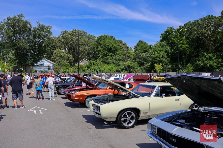 Classic American muscle cars lined up with spectators during Fuquay-Varina Cars and Coffee in North Carolina.