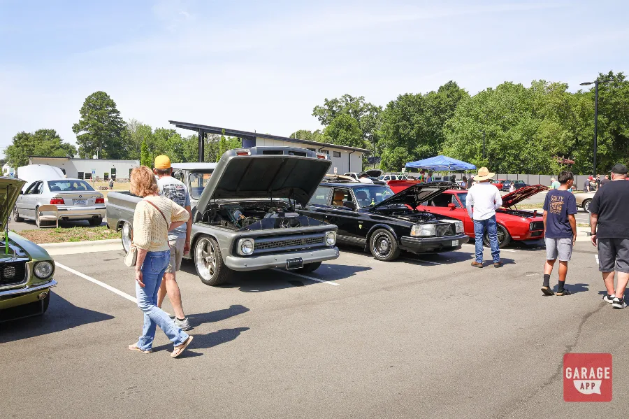 Classic American muscle cars lined up with spectators during Fuquay-Varina Cars and Coffee in North Carolina.