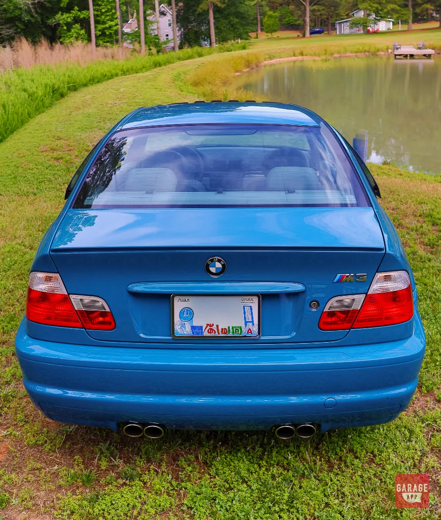 Rear view of a Laguna Seca Blue BMW M3 showcasing the wide rear track and iconic quad exhaust system.