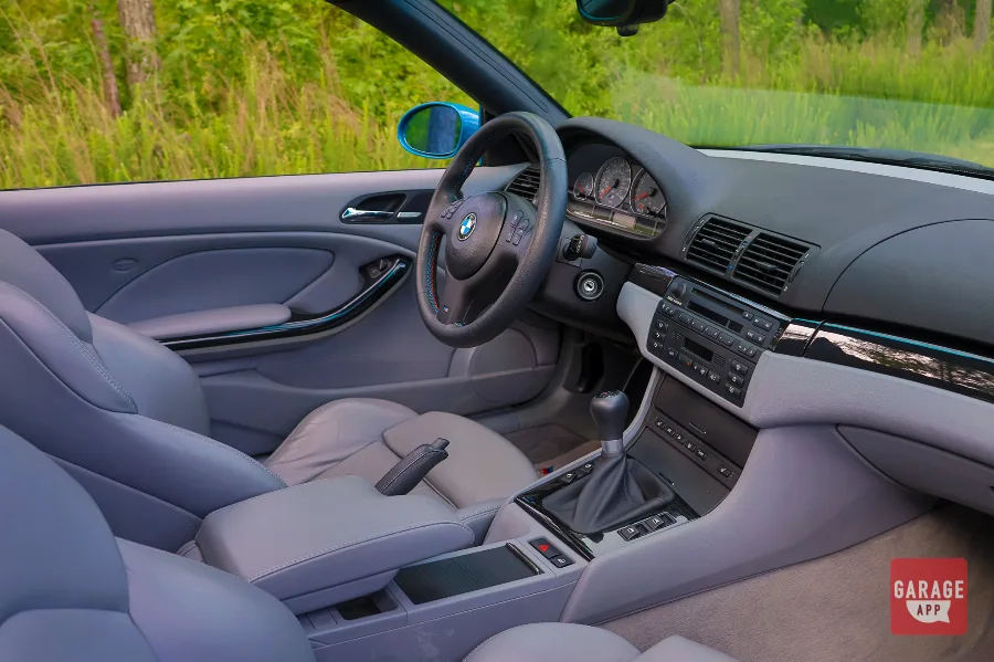 Interior of a 2005 BMW E46 M3 featuring a driver-focused cockpit, sport seats, analog gauges, and classic BMW M performance styling.
