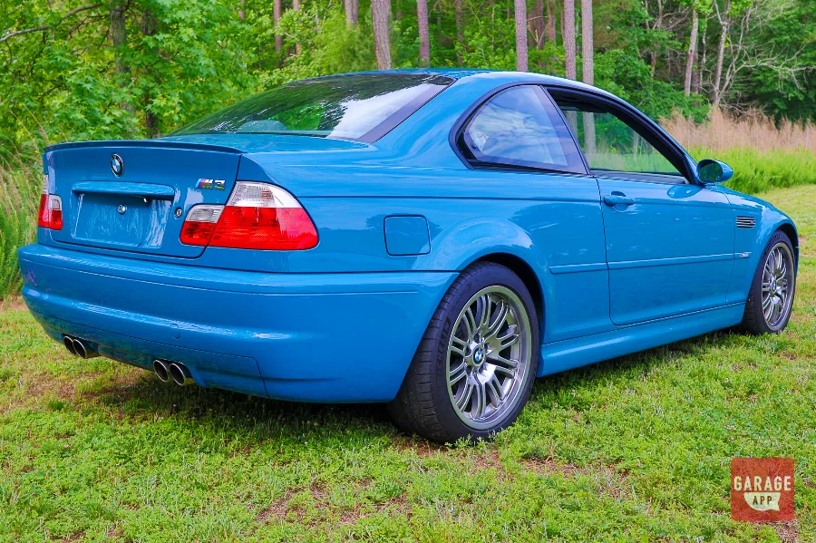 Rear three-quarter photograph of a 2005 BMW M3 featuring quad exhaust tips and distinctive Laguna Seca Blue paint.