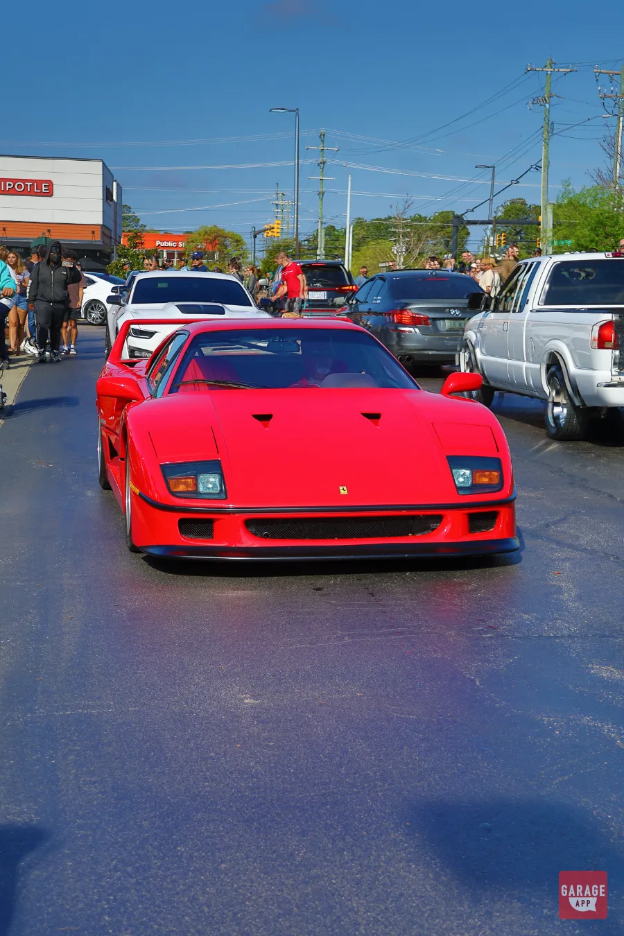 Red Ferrari F40 front view driving through Cars and Coffee lot
