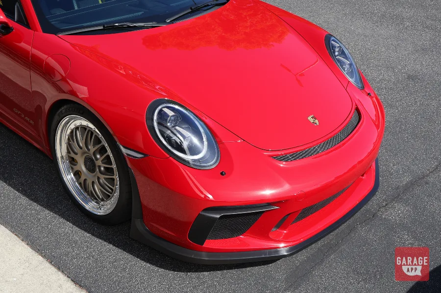 Close-up of a Guards Red Porsche 911 GT3 MR front end highlighting LED headlights, carbon fiber front aero components, and Manthey Racing performance upgrades.