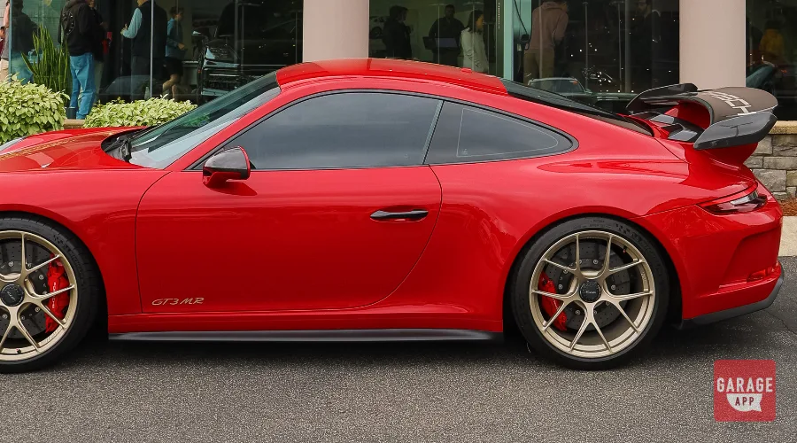Side profile of a Porsche 991.2 GT3 MR in Guards Red displaying its aerodynamic bodywork, fixed rear wing, center-lock wheels, and naturally aspirated GT3 proportions.