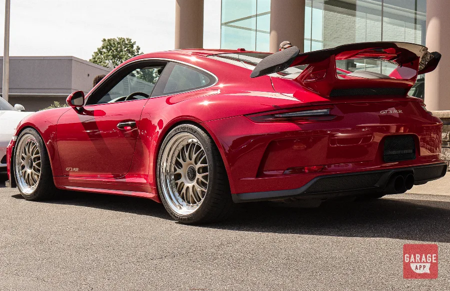 Rear three-quarter angle of a Guards Red Porsche 991.2 GT3 MR showing wide rear fenders, carbon aero elements, and the naturally aspirated Porsche GT3 platform.